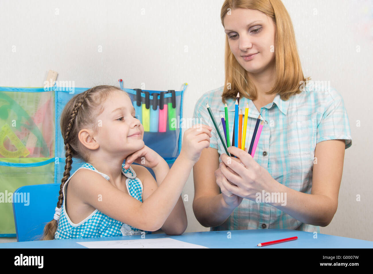 The five-year child picks a pencil in the hands of mother Stock Photo
