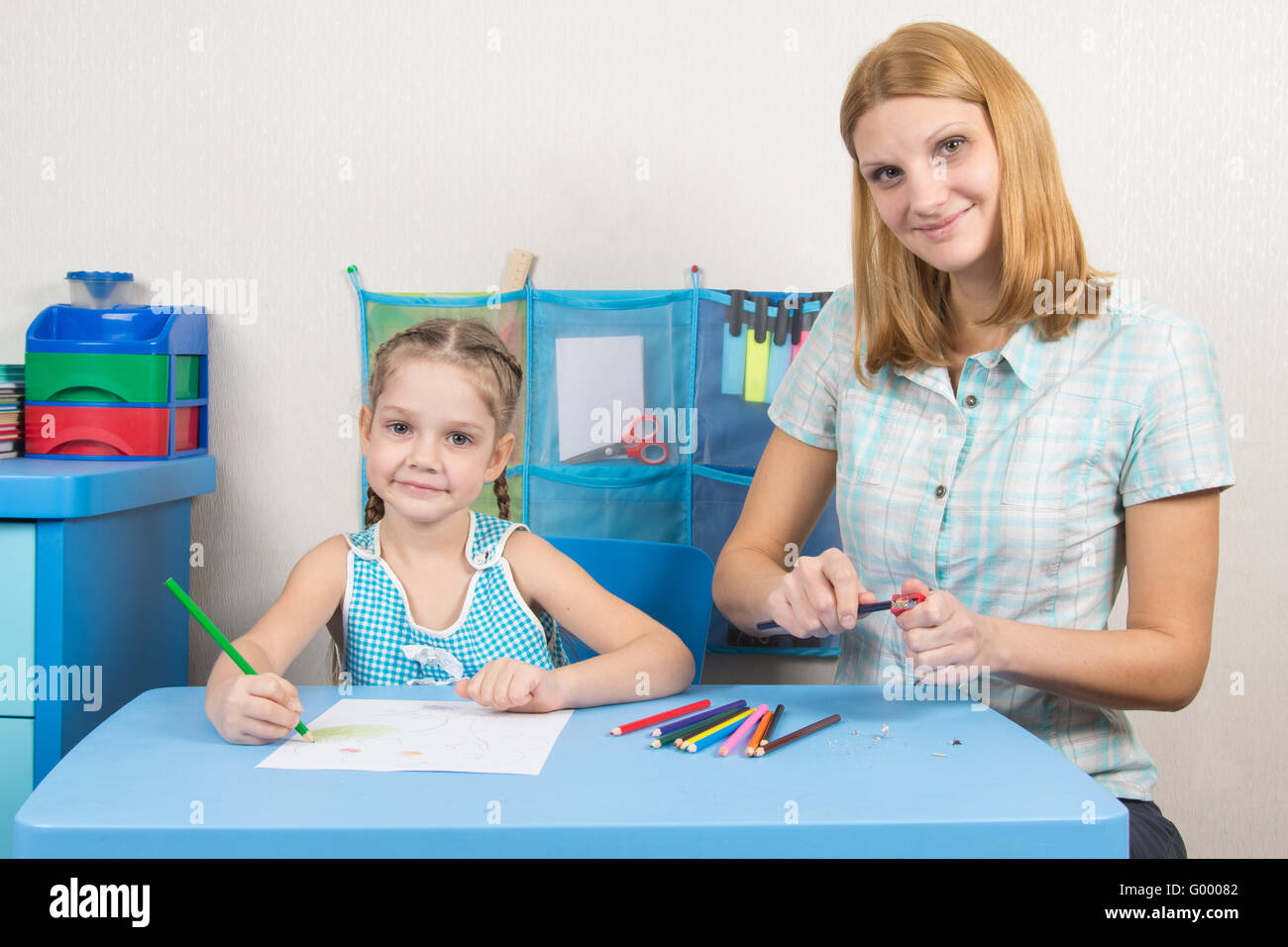 The five-year child draws on a sheet of paper, pencils undermines mom Stock Photo