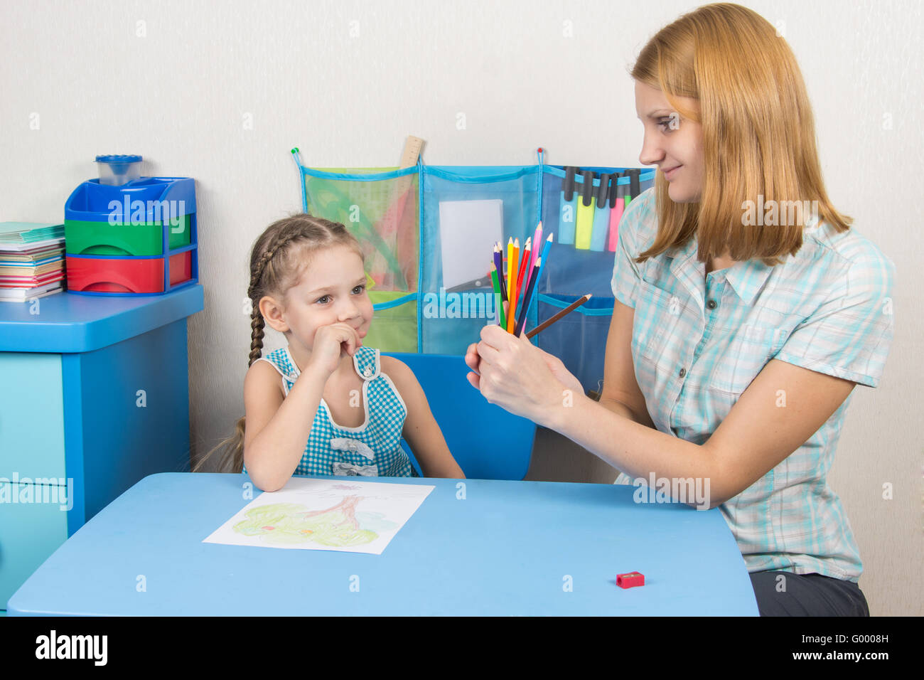 Five-year girl choose the right pencil from the teacher hands Stock Photo