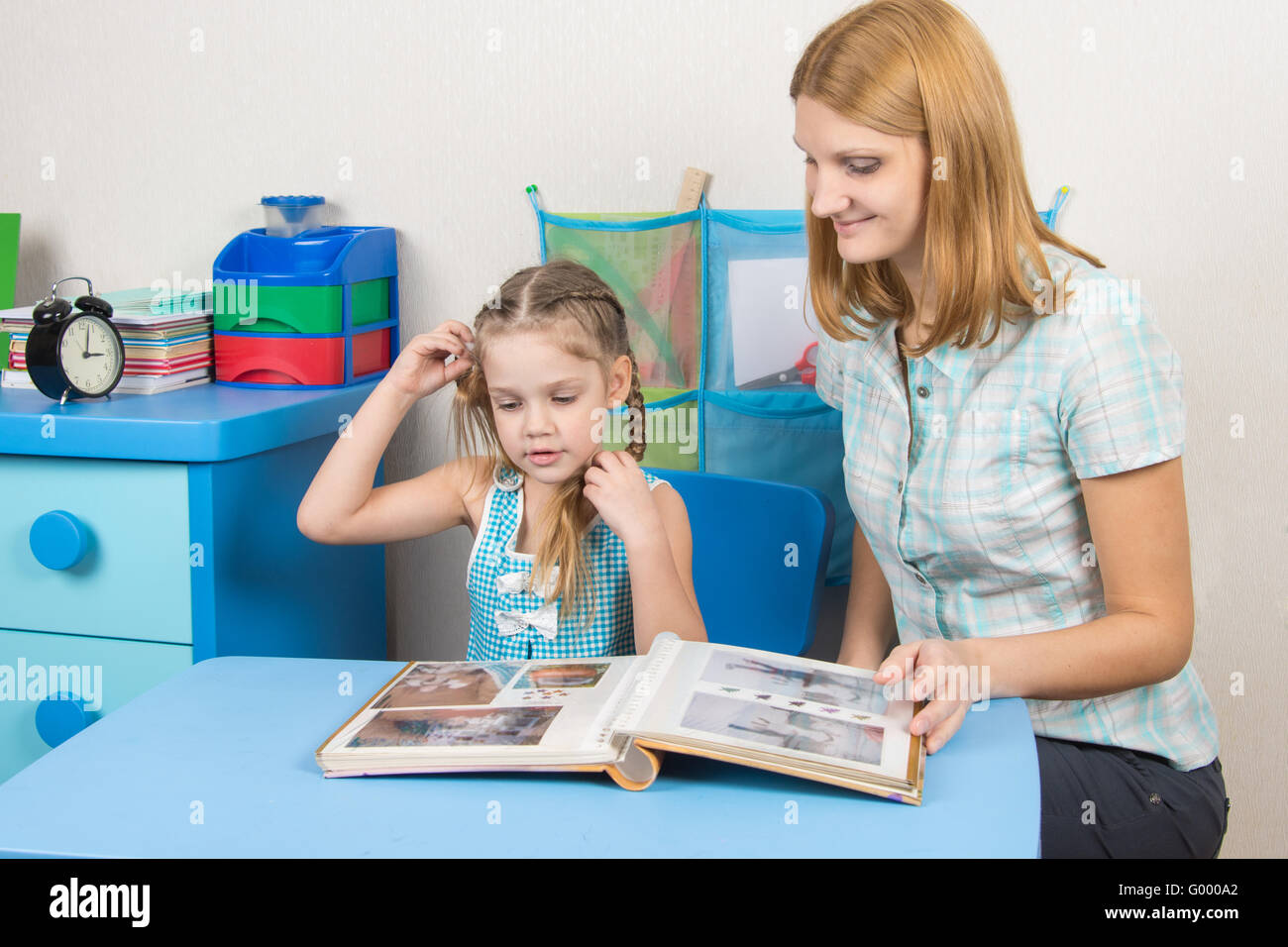 Mom shows her five-year-daughter photo album Stock Photo