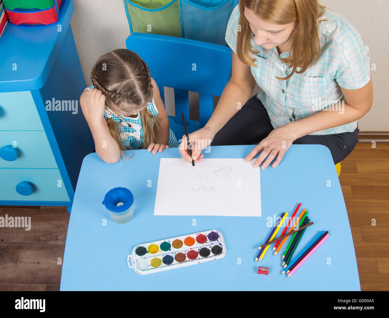 Mentor and five year old girl at the table draw a picture in kindergarten Stock Photo