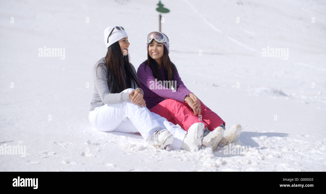 Two Friends Sitting Together on Sunny Ski Hill Stock Photo