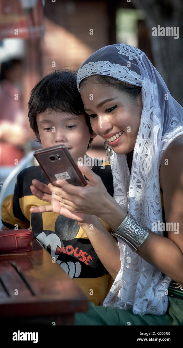 Mother and child looking at phone images. Asian woman smiling, happy, laughing. Stock Photo