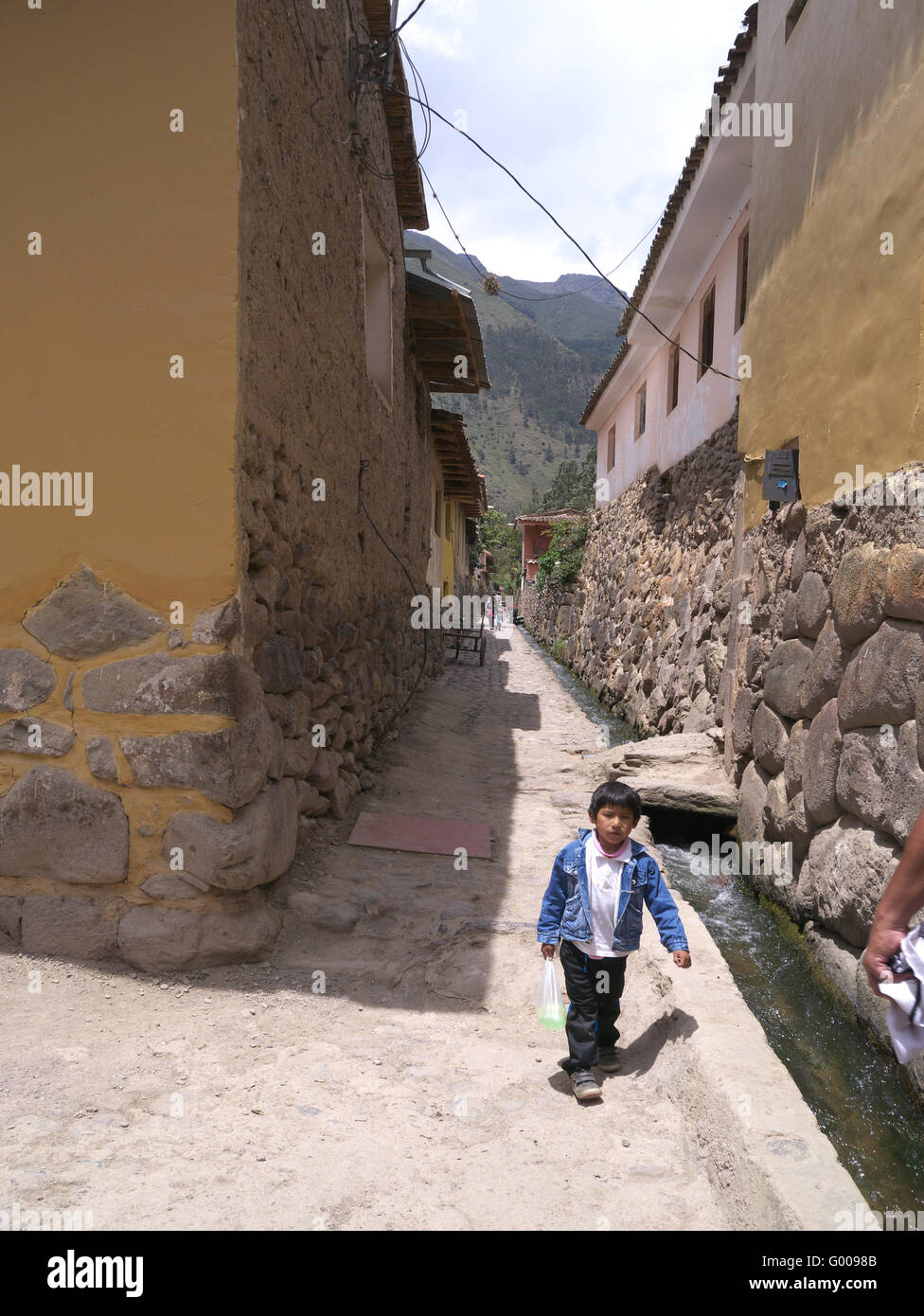 Boy walking down street built on Inca stones in Peru near Ollantaytambo ruins Stock Photo