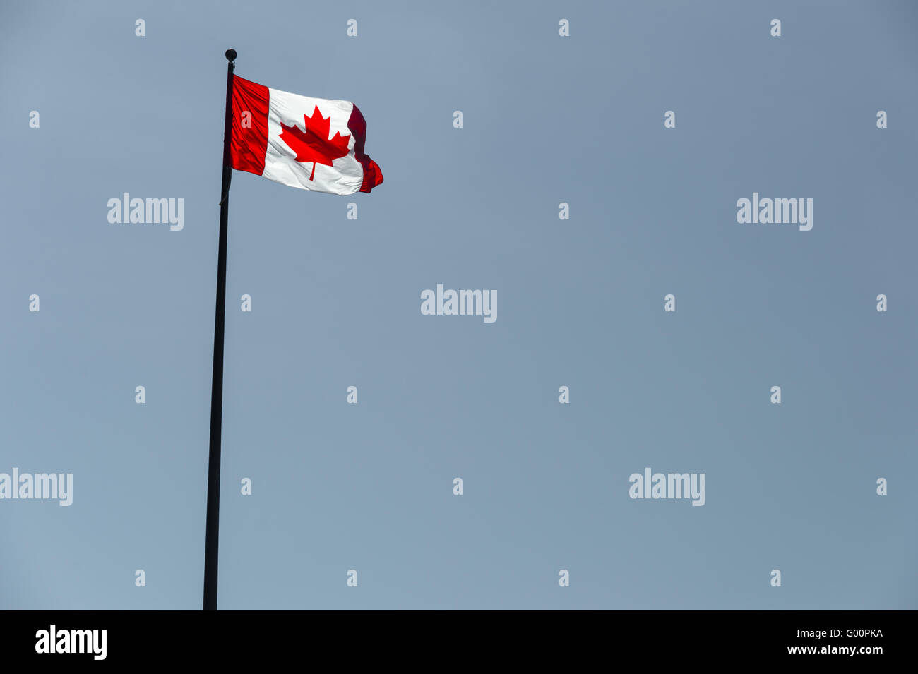 Canadian flag waving over pale blue sky Stock Photo