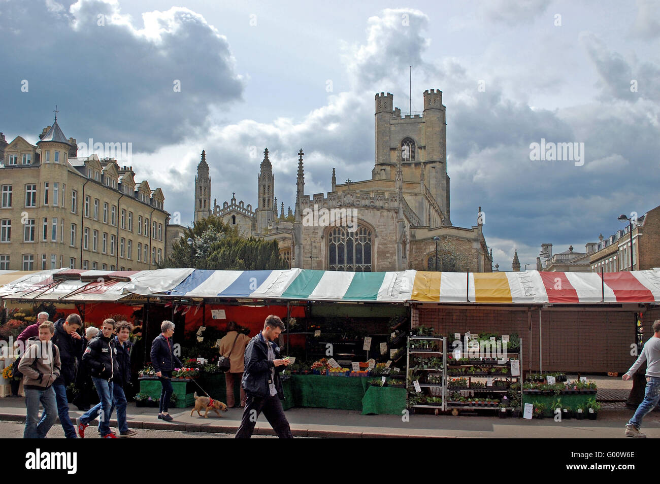Students stroll past the brightly colored awnings of Cambridge market with the ornate towers of Kings College, in the background Stock Photo