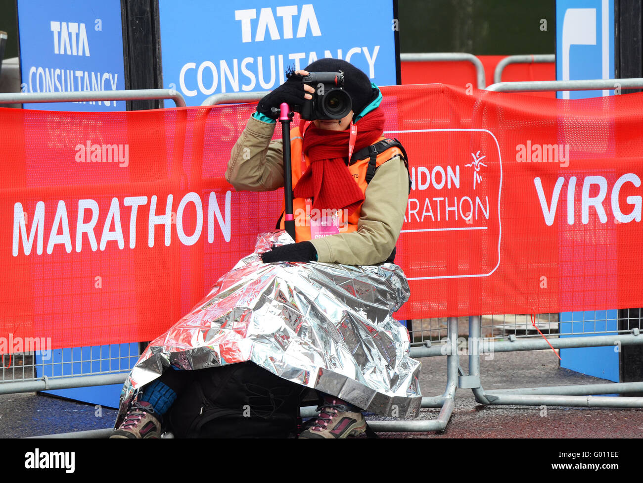 The Virgin Money London Marathon 2016. Female photographer covering the event wrapped in a foil blanket for warmth Stock Photo
