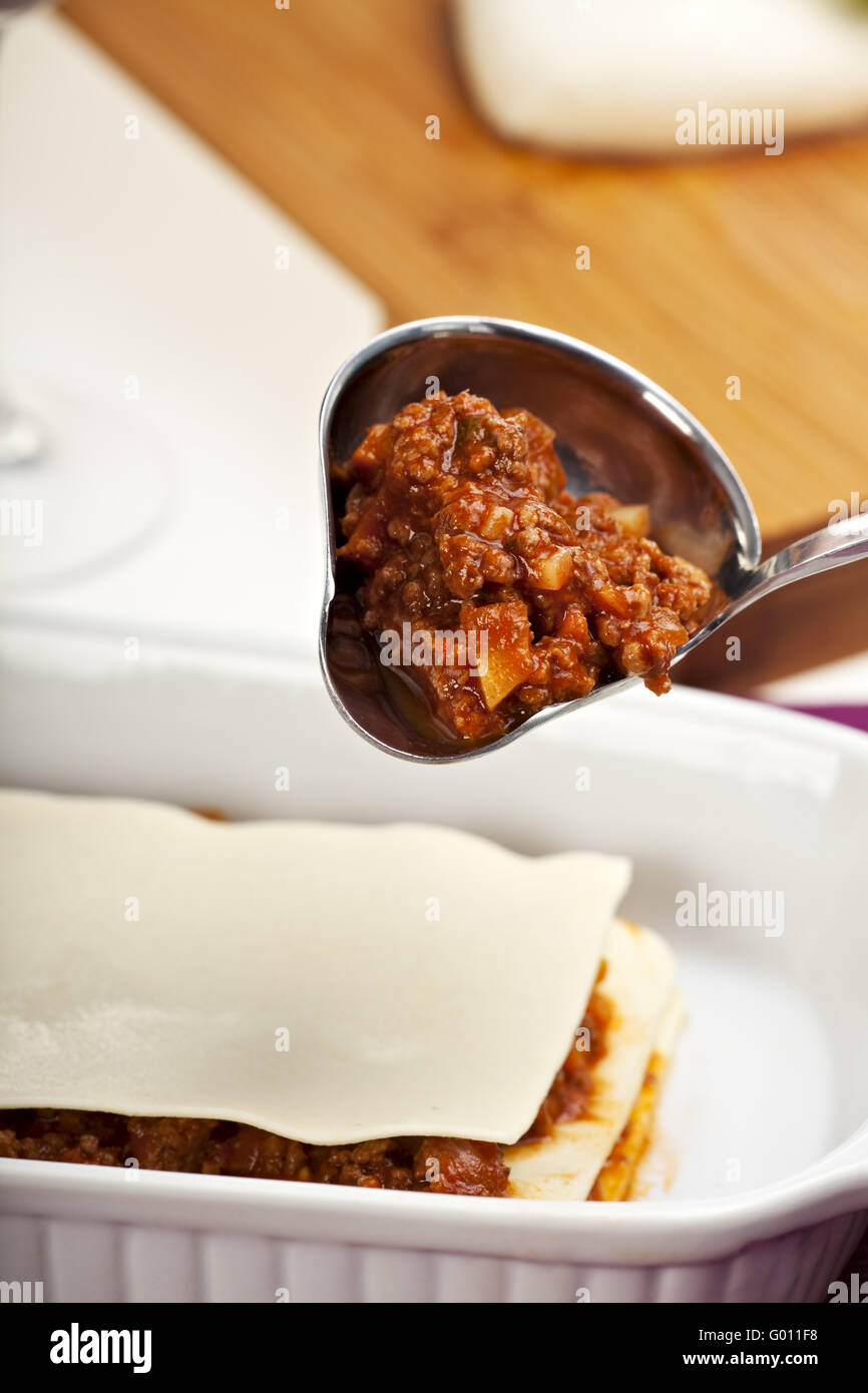 making a lasagna by pouring the sauce Stock Photo