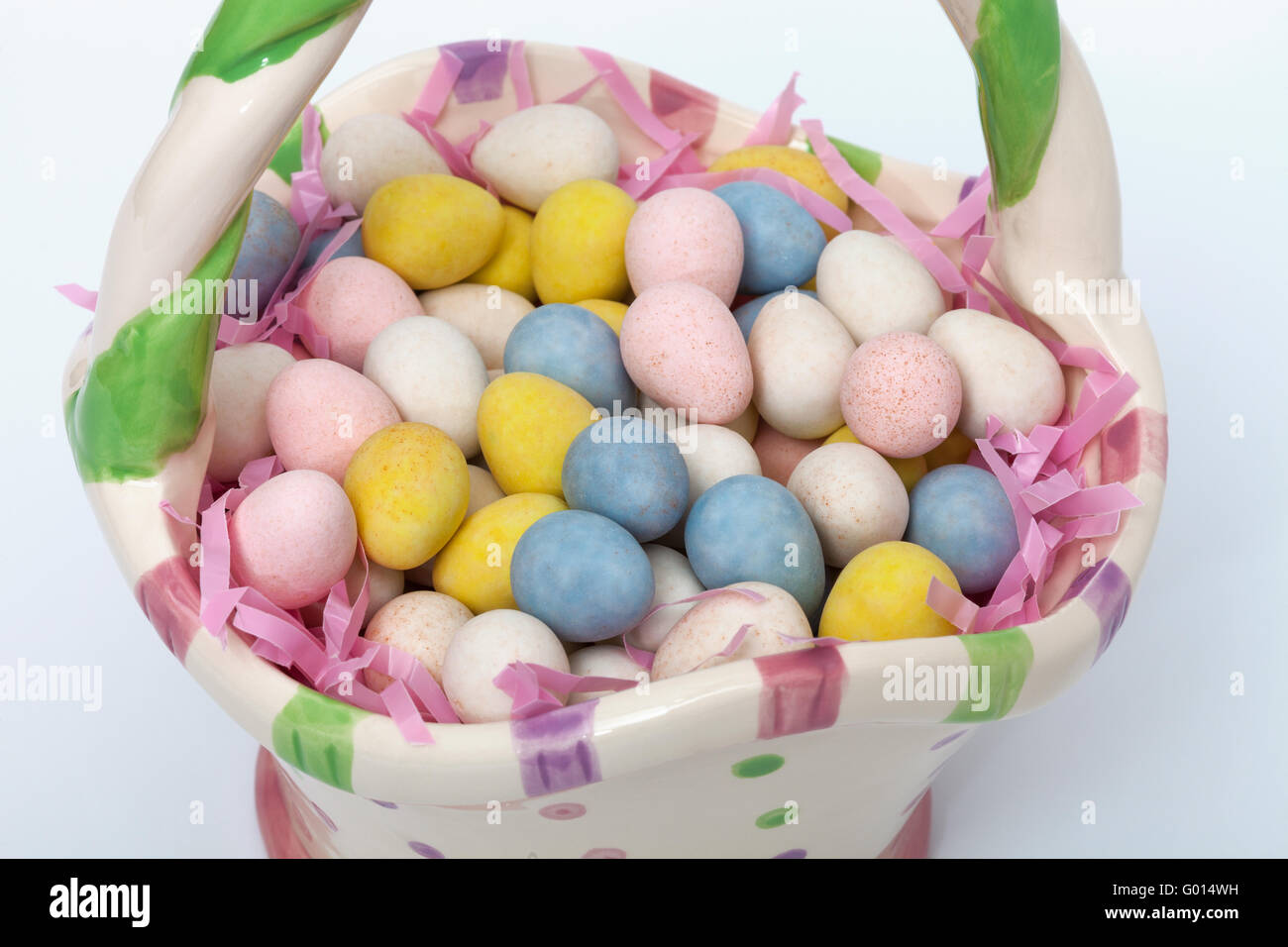 Candy covered Easter eggs in a ceramic basket Stock Photo