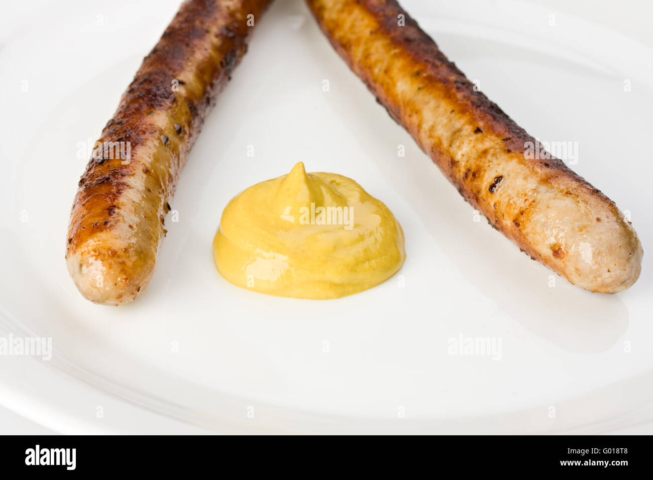 two grilled sausages on a plate with mustard Stock Photo