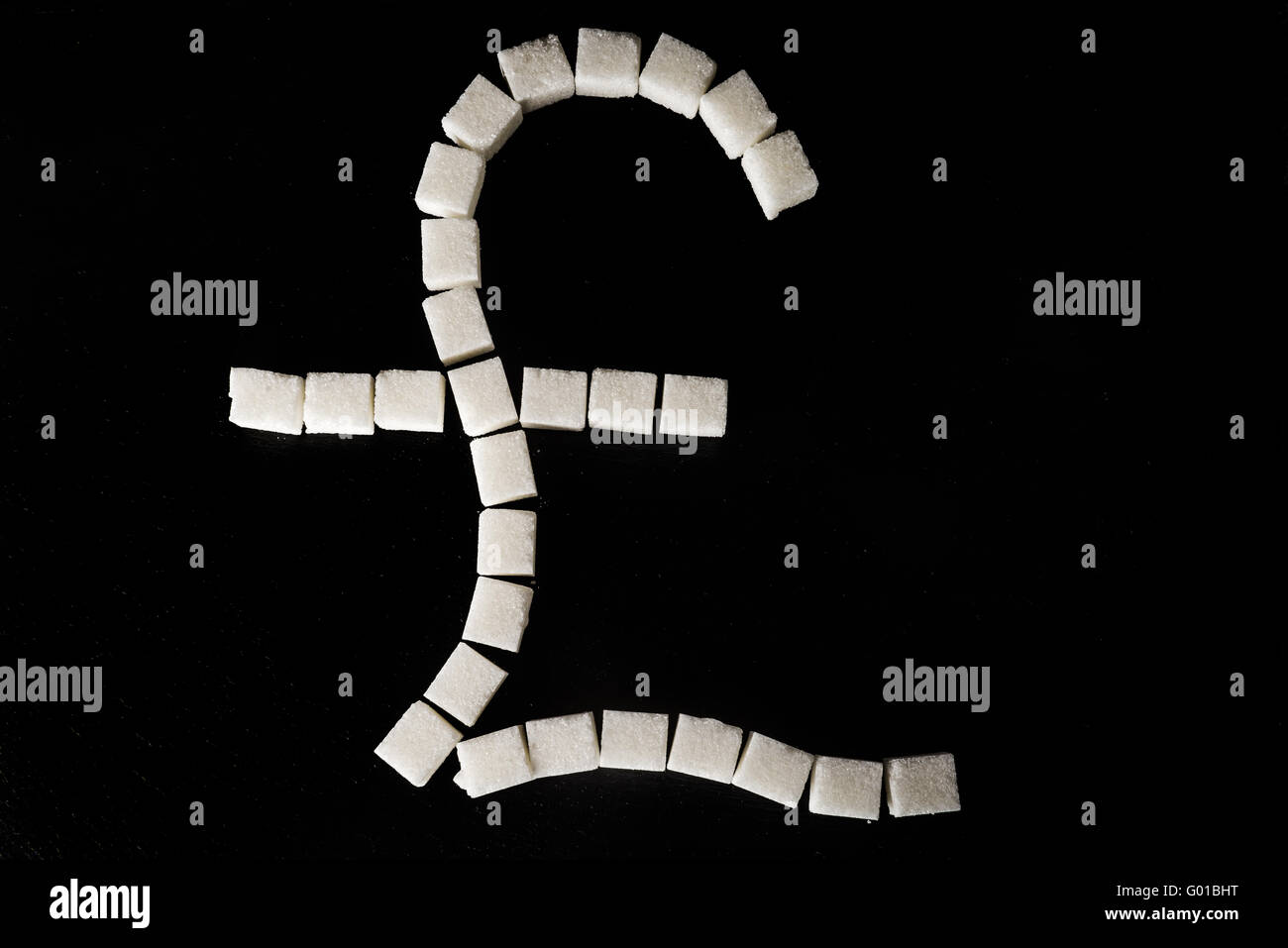 Pound sign made of white refined sugar cubes on black slate background, symbolising sugar tax Stock Photo