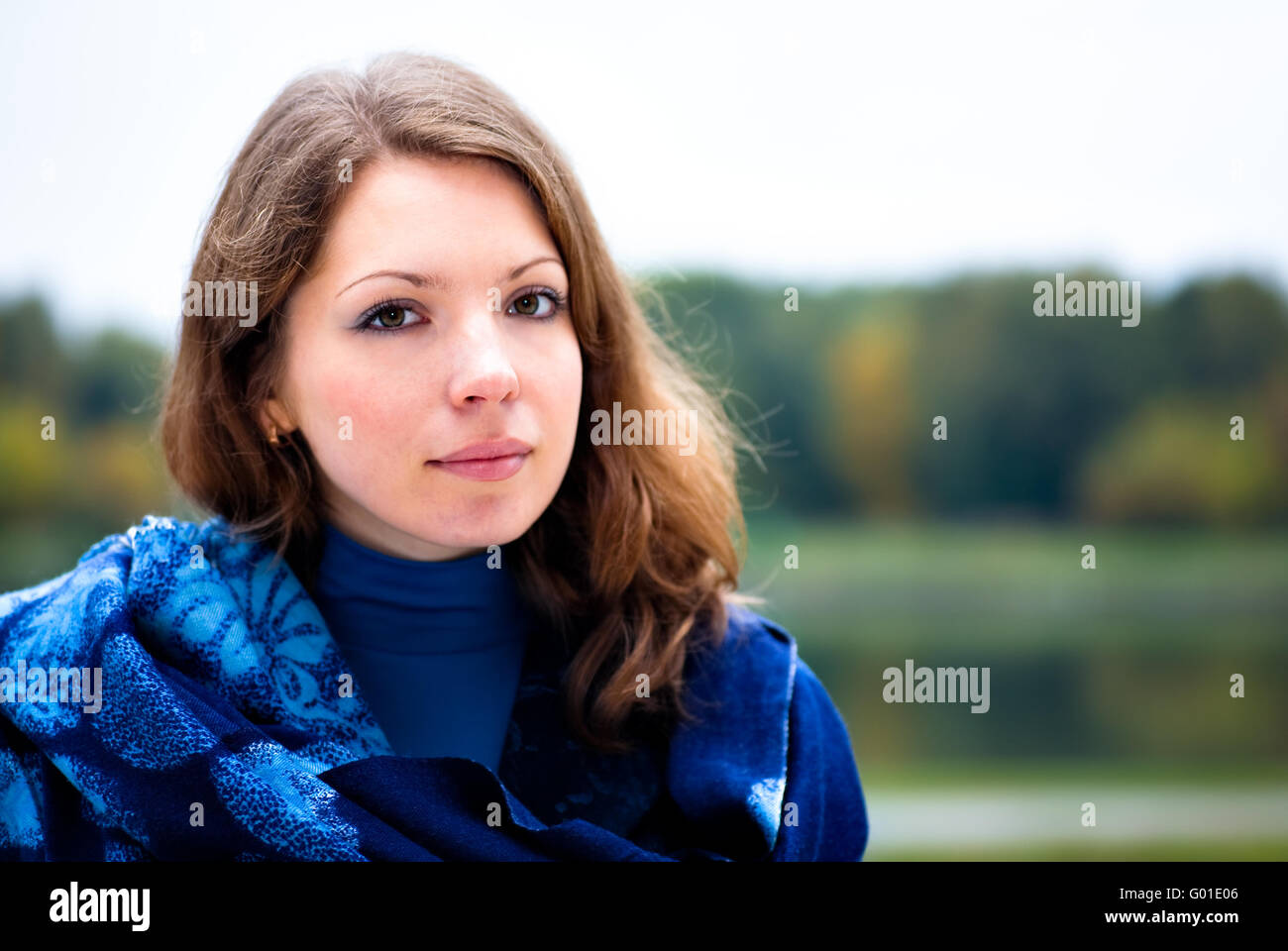 Portrait of pretty young woman with shawl against autumn forest landscape Stock Photo