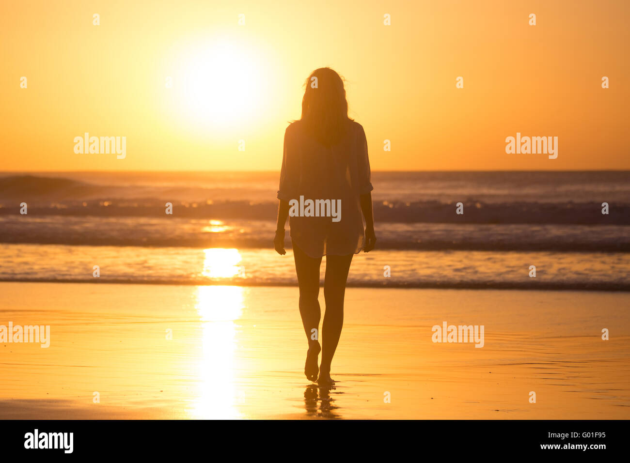 Lady walking on sandy beach in sunset Stock Photo - Alamy