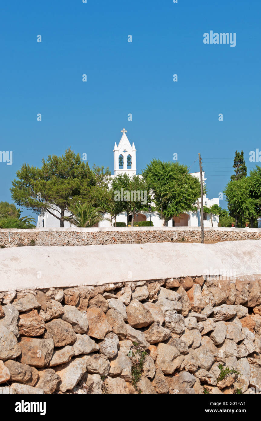 Menorca, Balearic Islands, Spain, Europe: a stone wall and a white church in the menorcan countryside Stock Photo