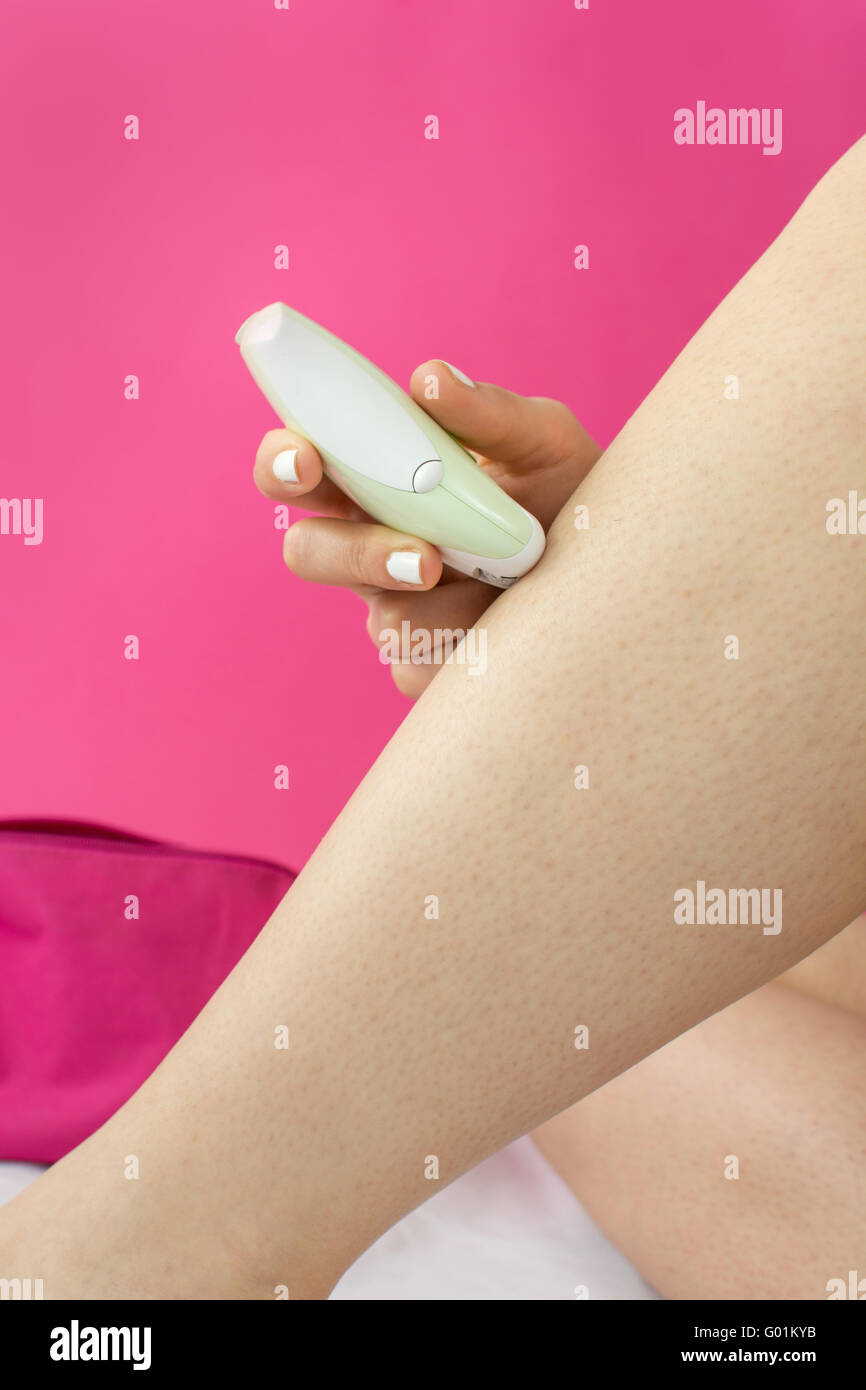 Woman epilates her leg with an electric epilator device Stock Photo Alamy