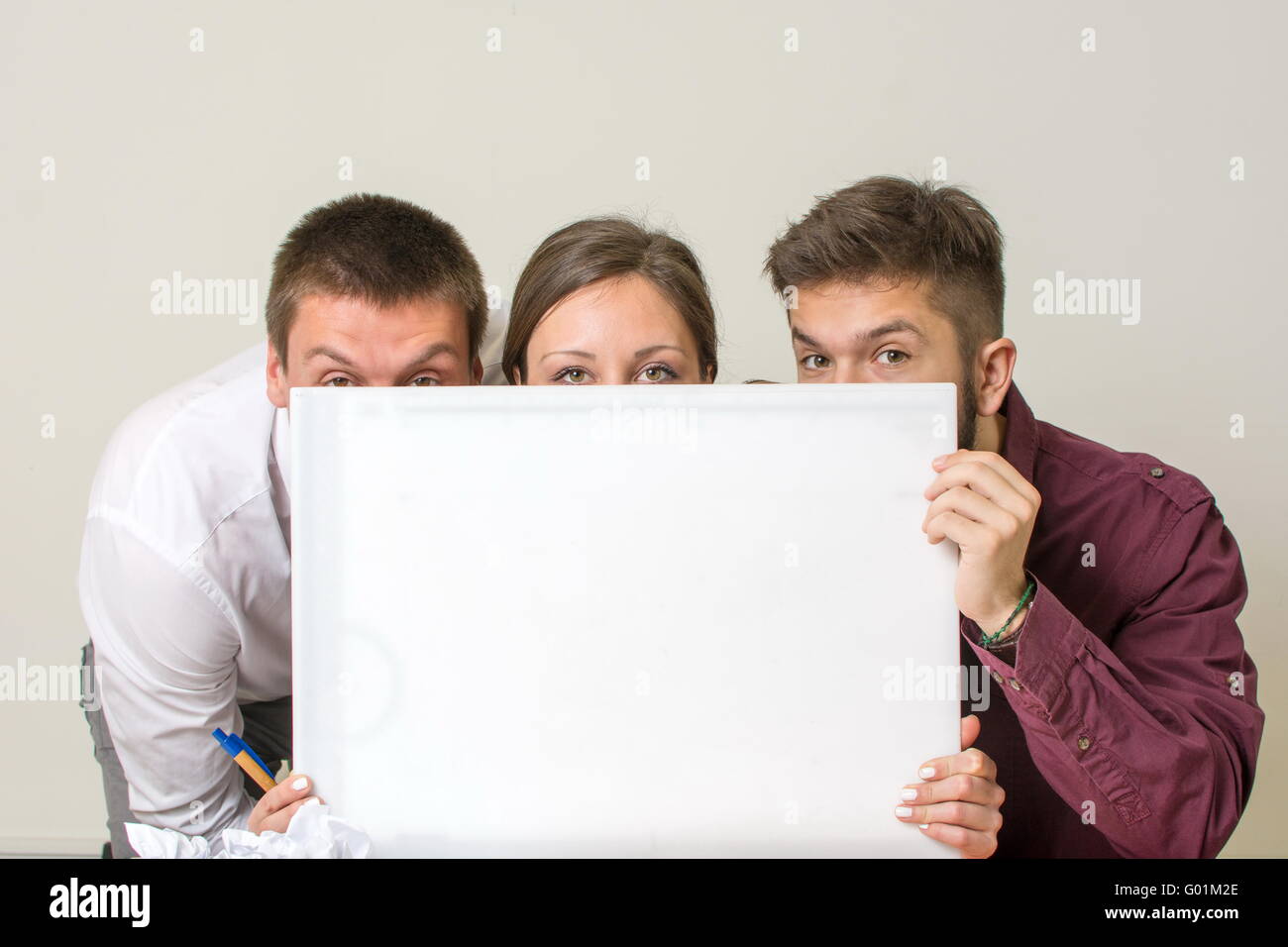 Our new project. Team hiding behind white board Stock Photo