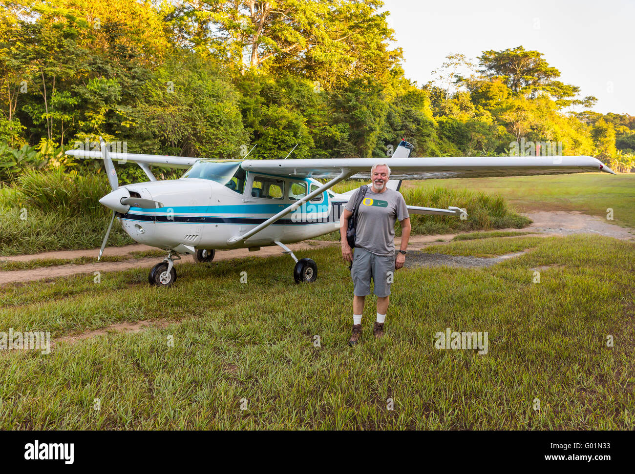 CORCOVADO NATIONAL PARK, COSTA RICA - Small plane, Cessna, and ecotourist on grass landing strip, Osa Peninsula. Stock Photo