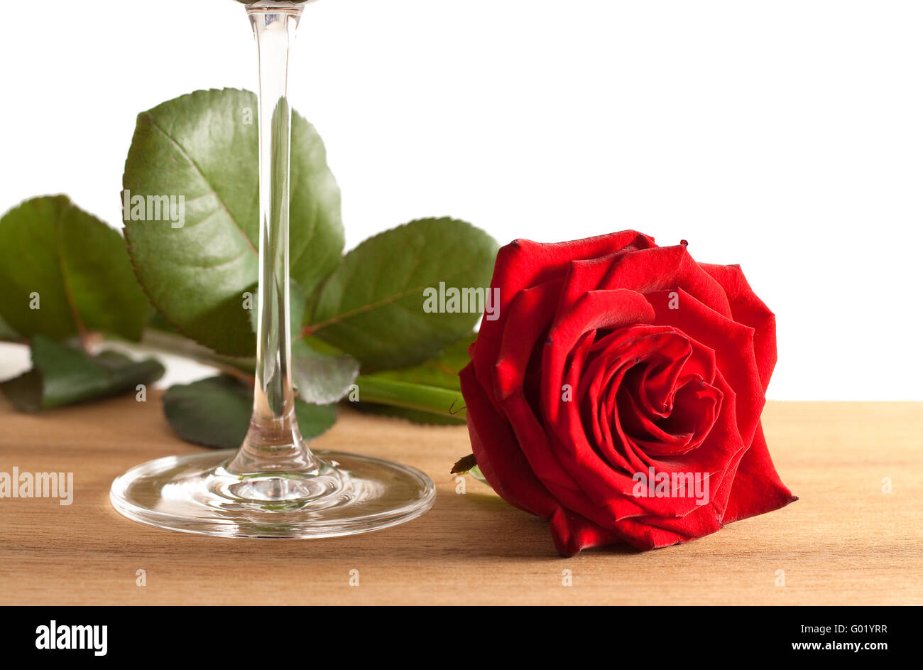 A red rose and a wine glass on a wooden bottom isolated on white ...