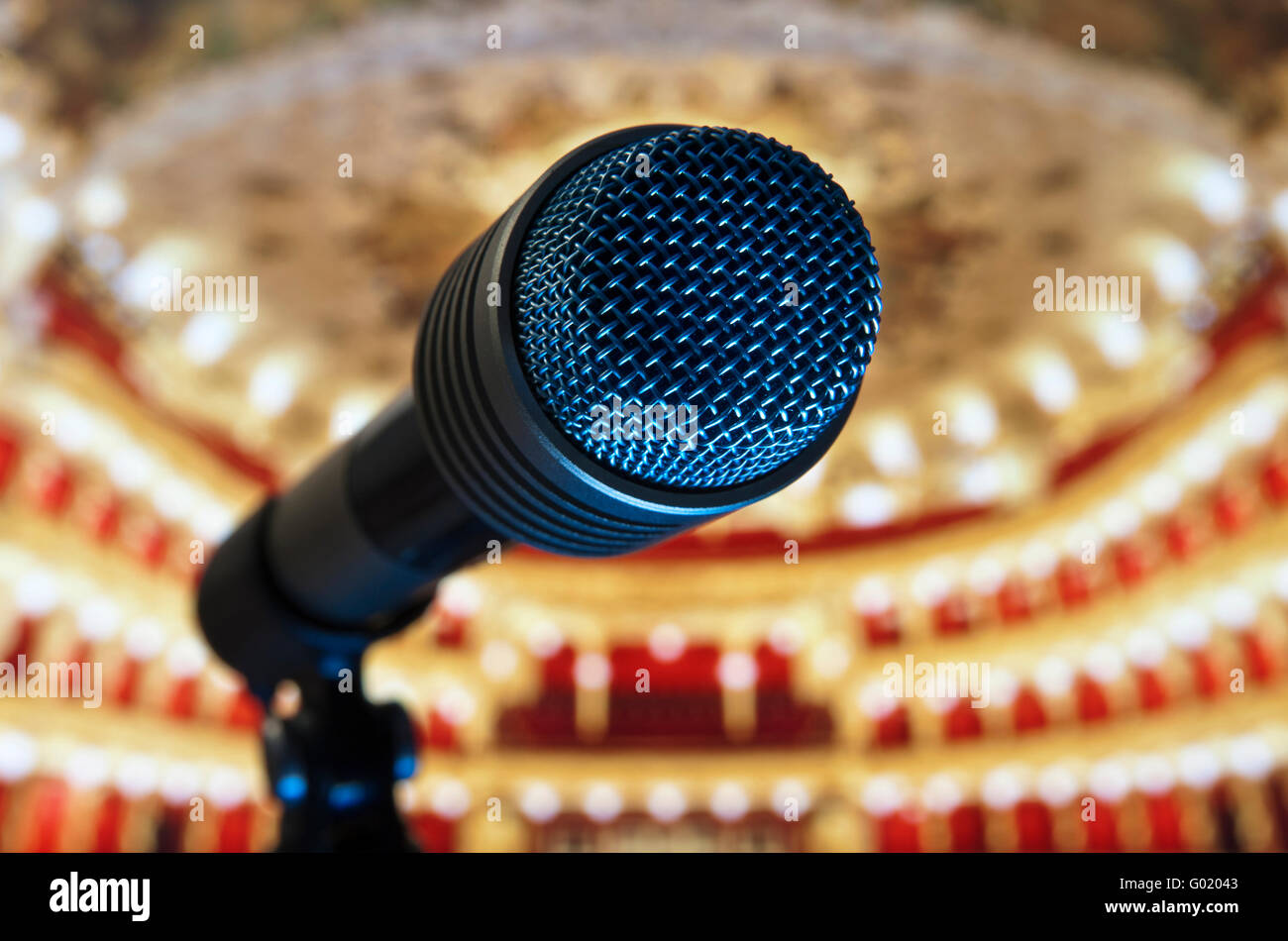 Microphone close up on stage with plush traditional empty theatre