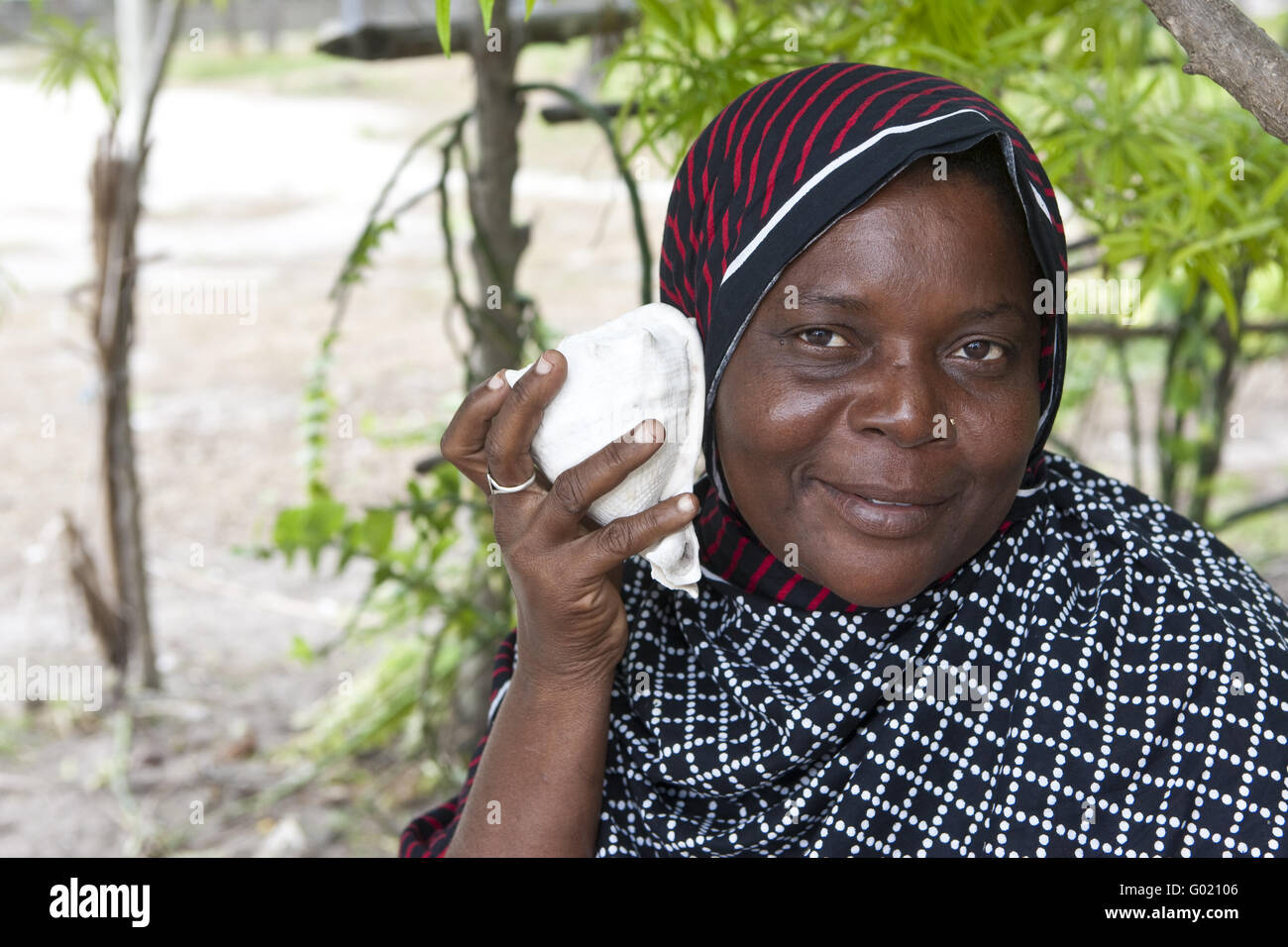 An old woman holding a seashell to your ear to hear sounds of the sea m Stock Photo