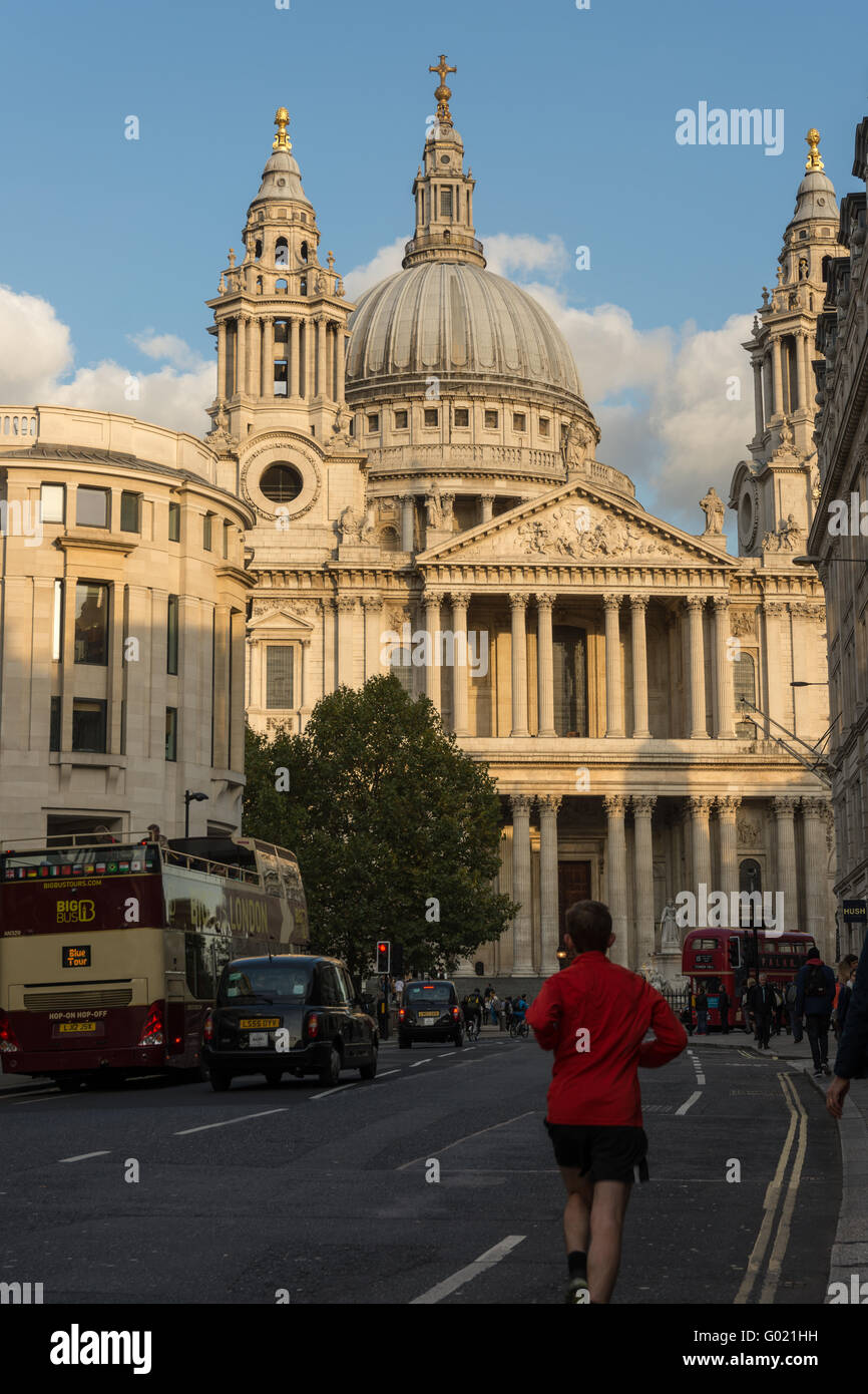A view of the front of St Paul's Cathedral, London, England from Ludgate Hill with a jogger and traffic in the foreground Stock Photo