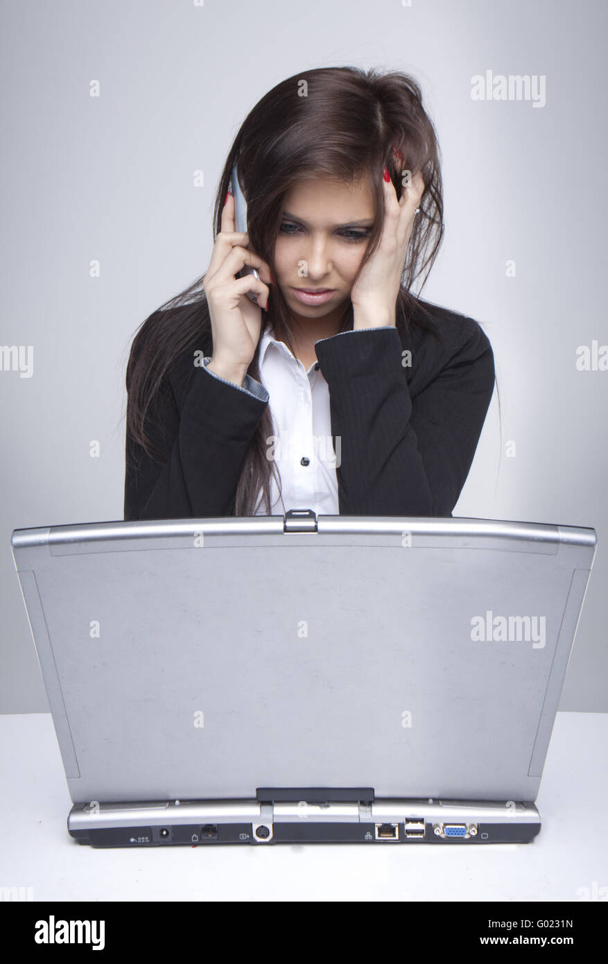 unhappy woman having problems with computer trying to reach support line Stock Photo