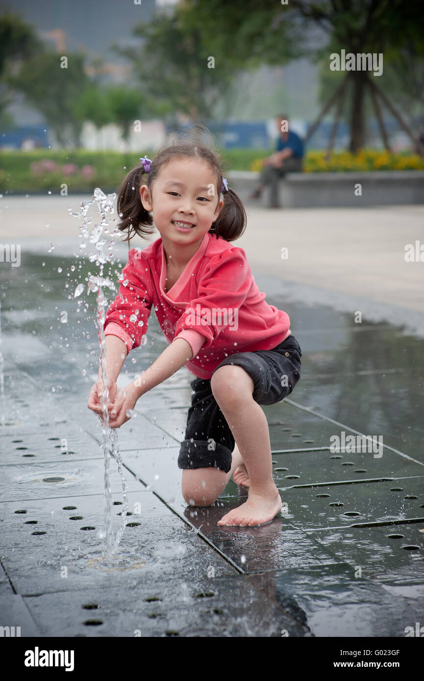 happy asian girl play by Fountain Stock Photo - Alamy