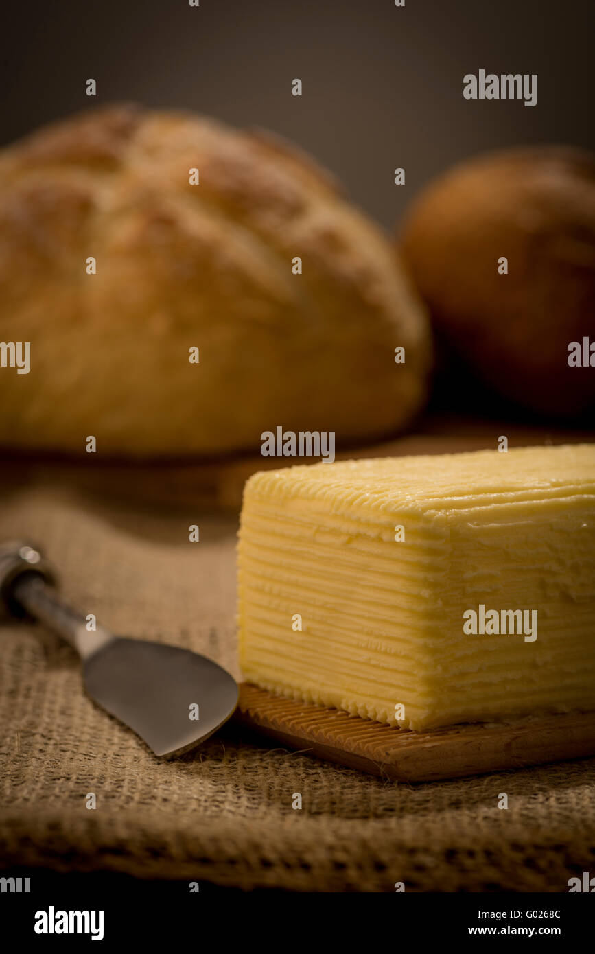 Hand churned homemade butter on wooden paddles with butter knife and loaf of bread. Stock Photo