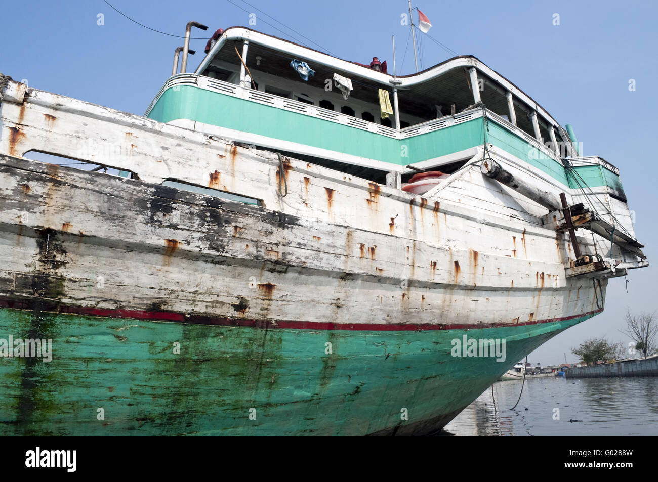 Blue rusty vessel in a canal in Jakarta harbor Stock Photo