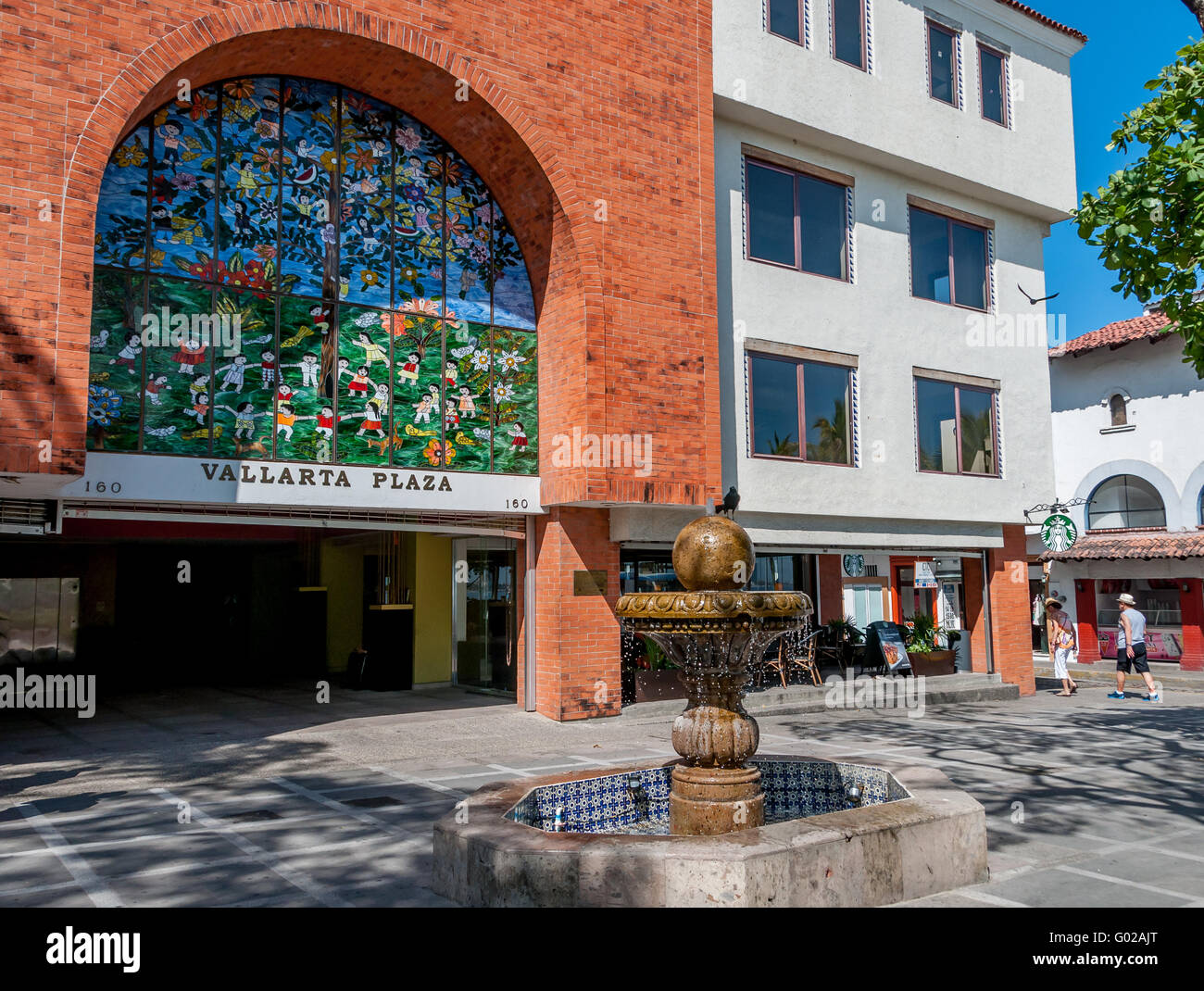 Stained glass by Manuel Lepe at Vallarta Plaza, bird on fountain, and toursits walking through Old Town square, Romantic Zone, Puerto Vallarta Stock Photo