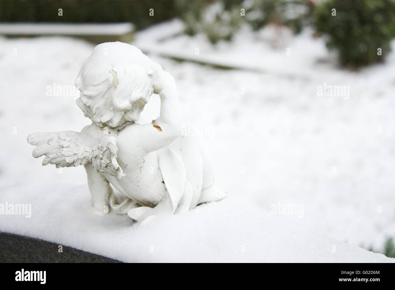 Angel statue on a cemetery with snow looking to the graves. Stock Photo