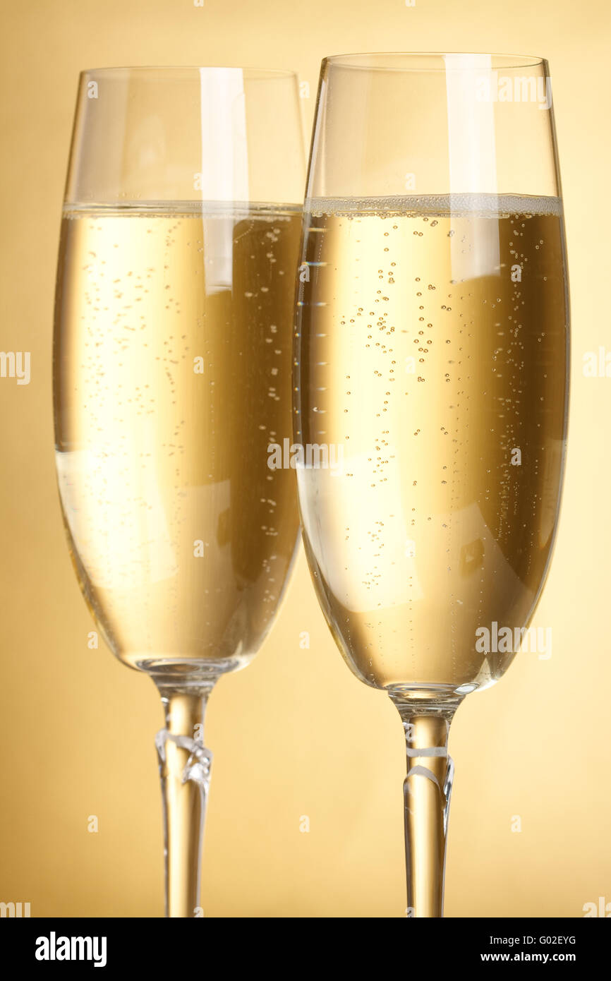 Two flutes with champagne on golden background Stock Photo