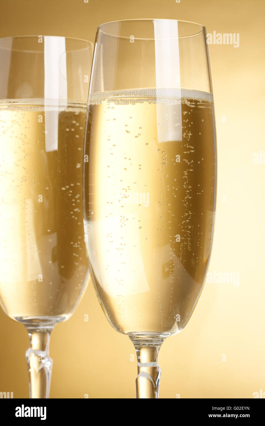 Two flutes with champagne on golden background Stock Photo