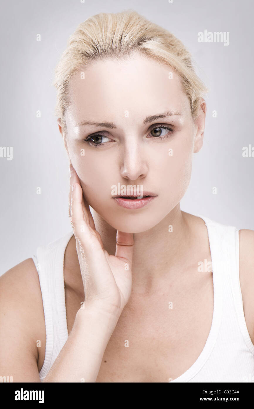 portrait of a caucasian blonde woman with toothache on grey background Stock Photo