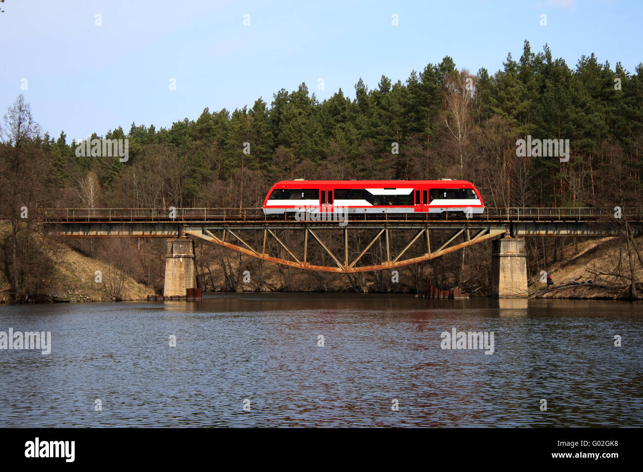 Railbus passing through the steel bridge over the lake Stock Photo
