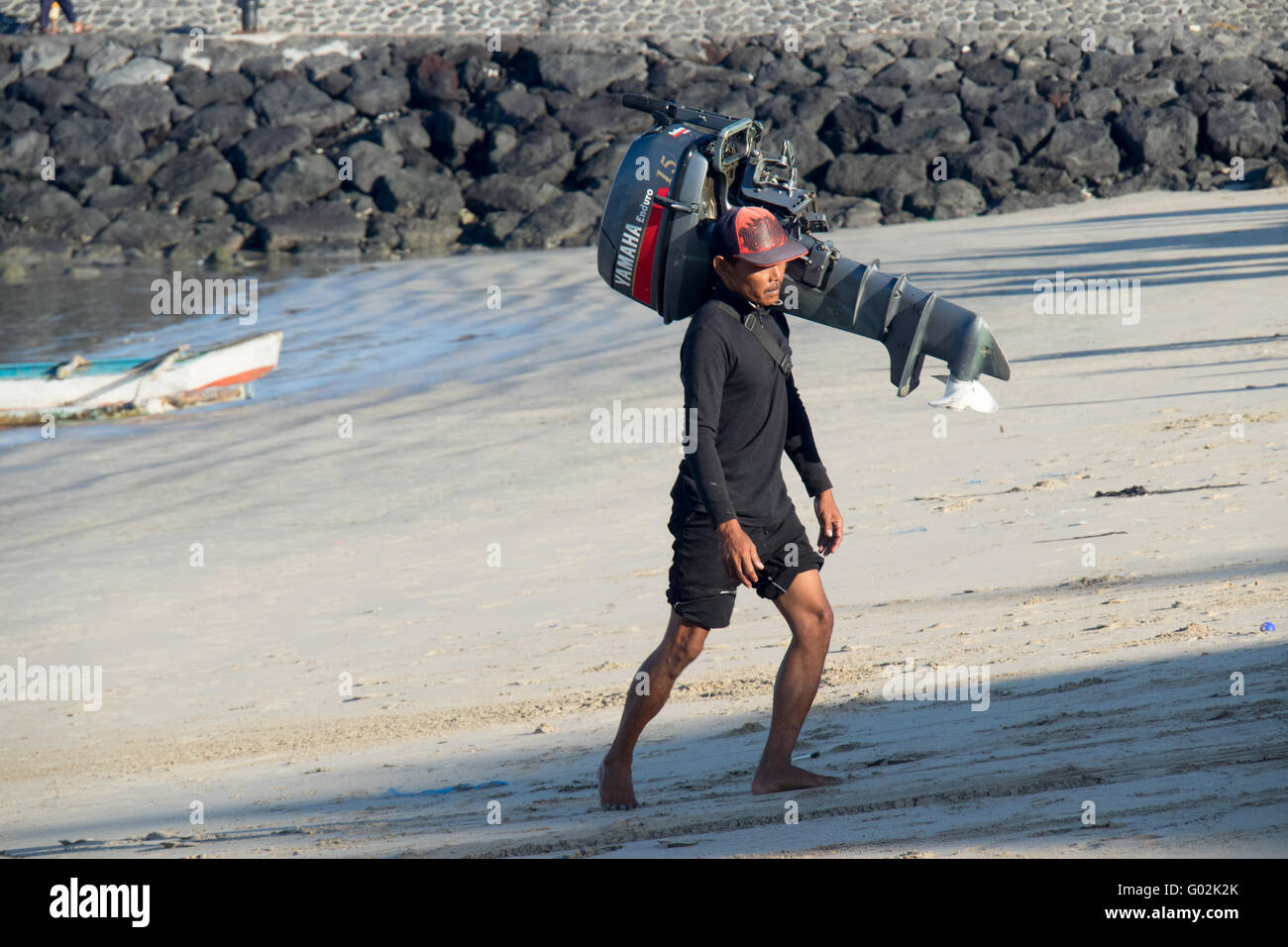 A man carrying an outboard motor on his shoulder. Stock Photo