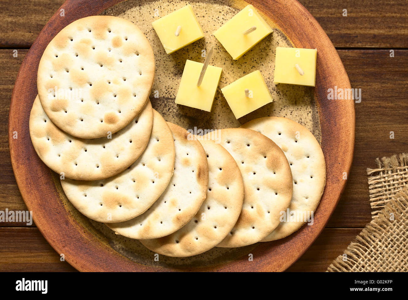 Saltine or soda crackers with cheese pieces served on plate