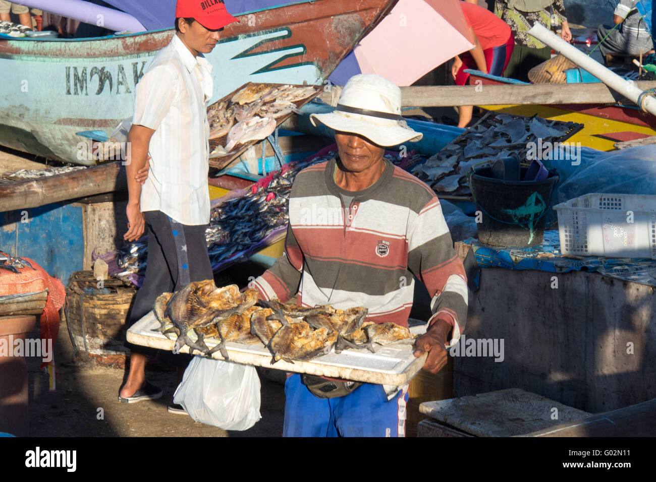 A man carrying a tray of dried fish at the Jimbaran Bay Fish Markets. Stock Photo