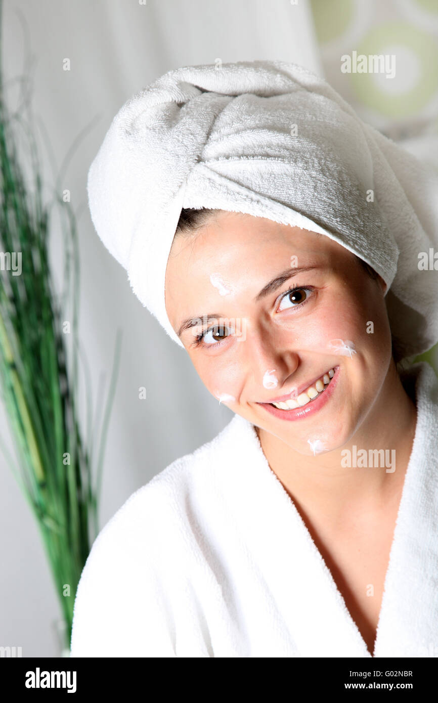 Junge Frau mit Creme im Gesicht lächelt entspannt- Smiling young woman with cream on her face relaxed. Stock Photo