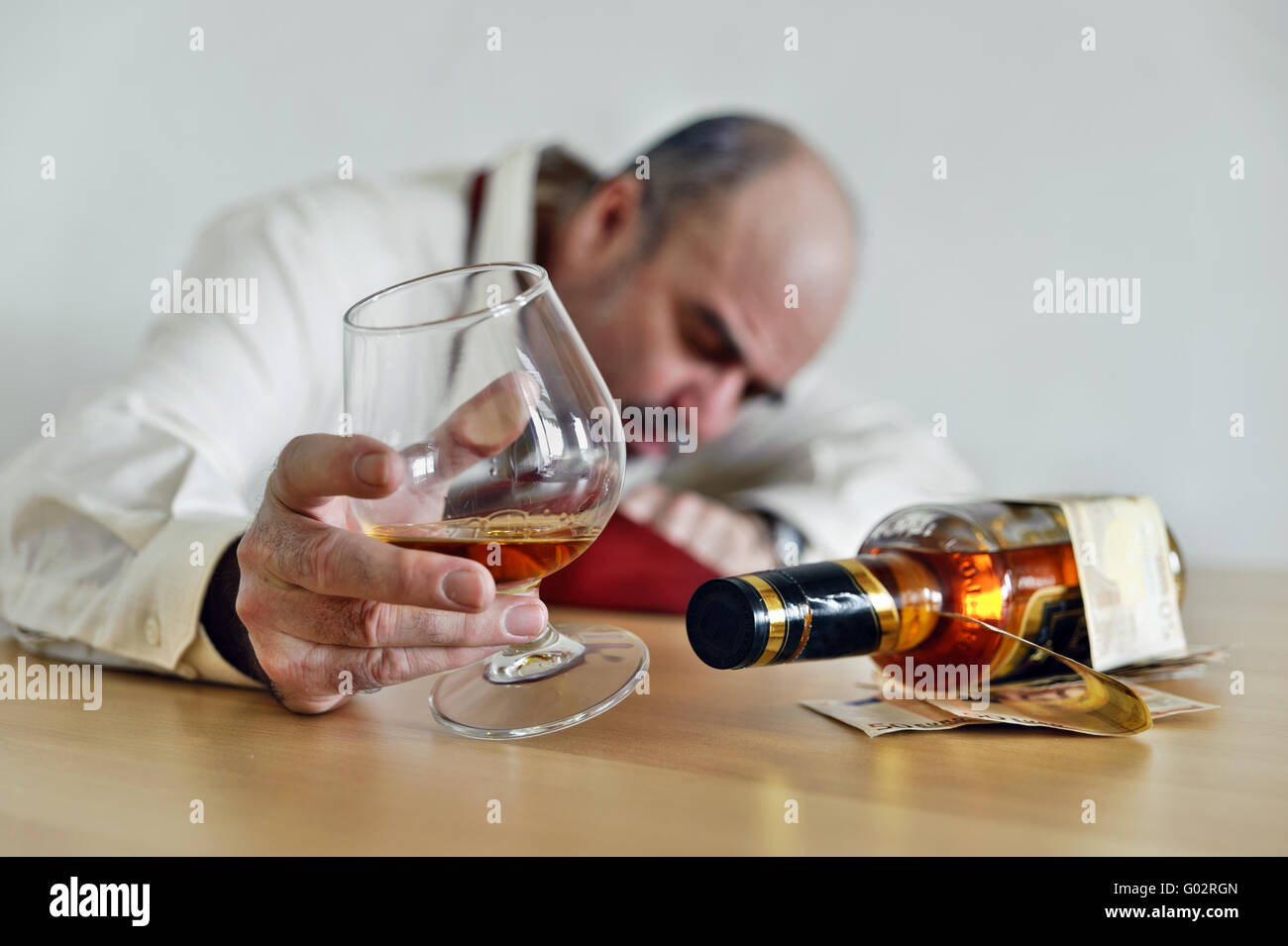 Alcoholic sitting with a cognac and a bottle of br Stock Photo