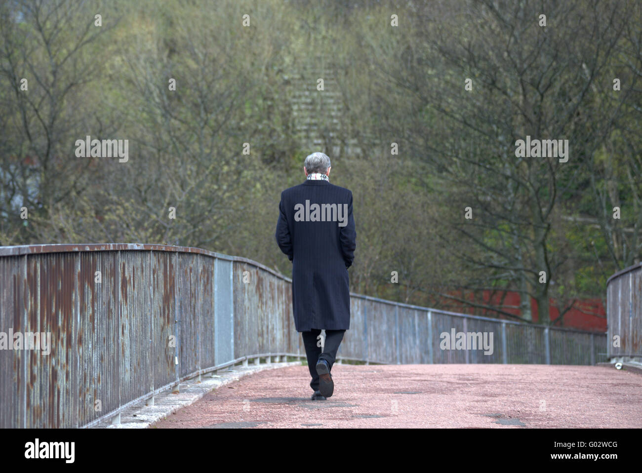 man in long  dark coat walking on path alone Stock Photo