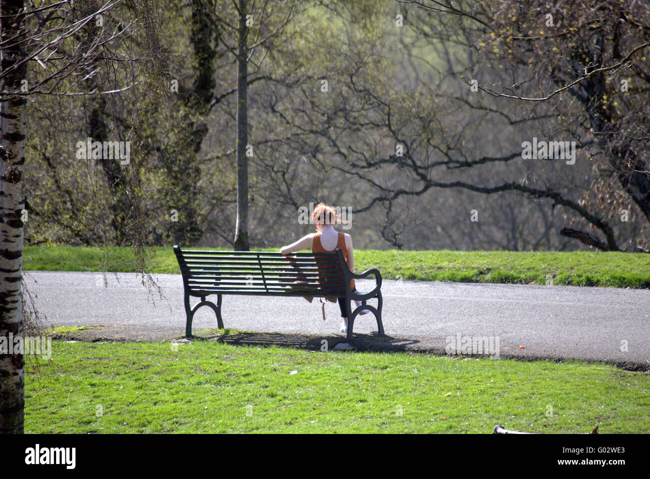 red haired athletic girl on bench kelvingrove park, Glasgow in Scotland Stock Photo