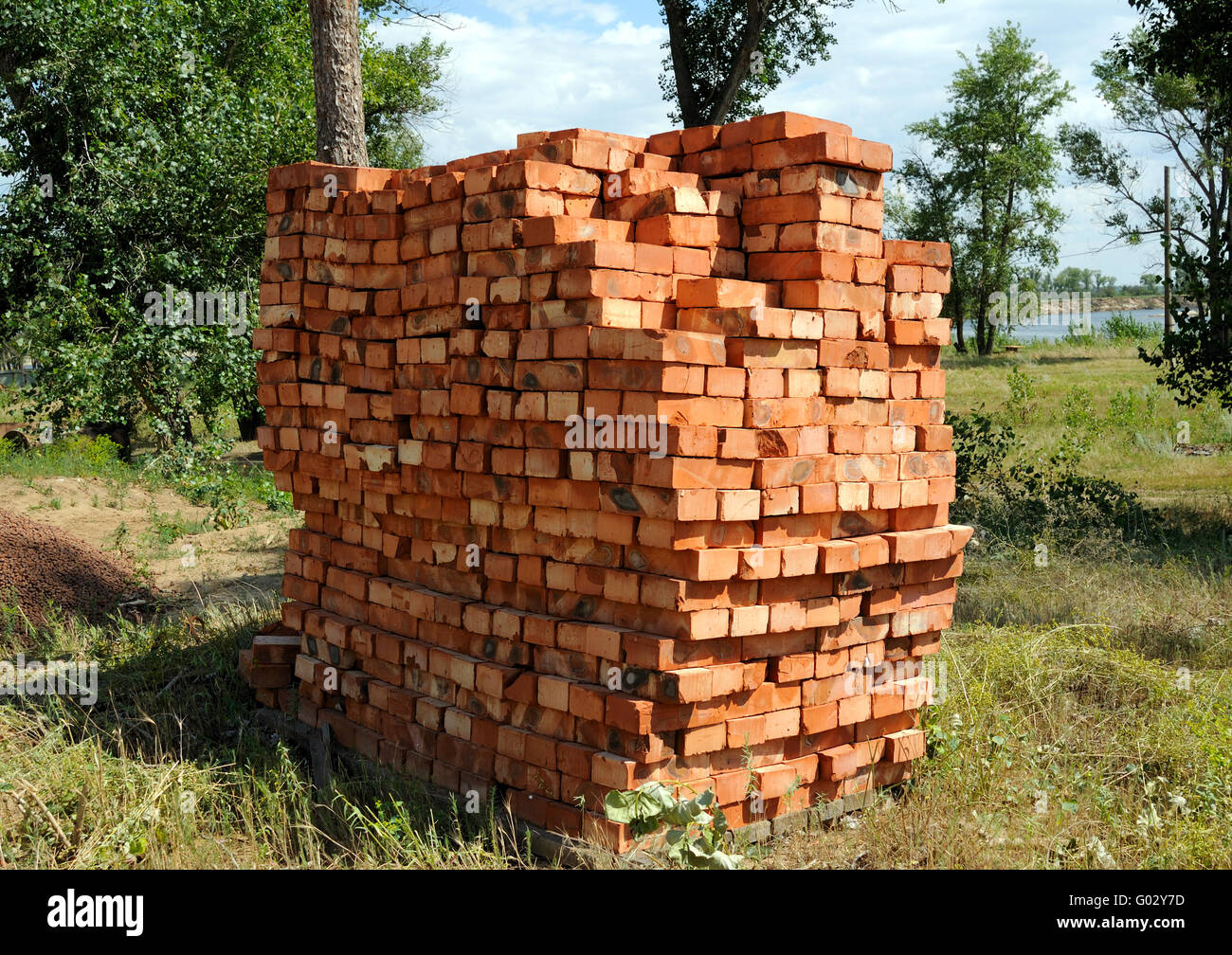 A pile of new red bricks at construction site sitting on wooden flat ...