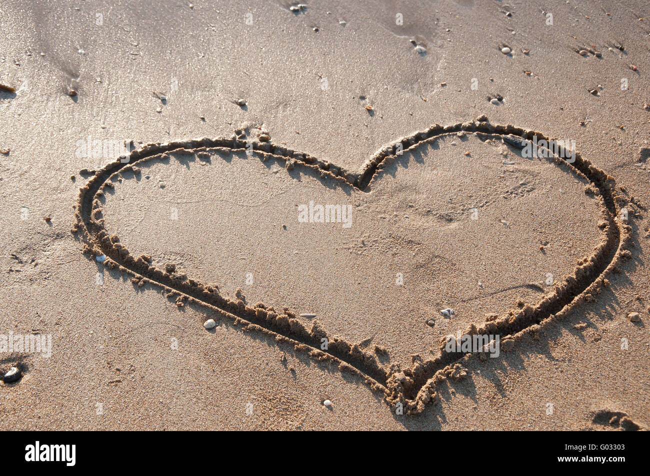 heart drawn in the sand on the beach Stock Photo