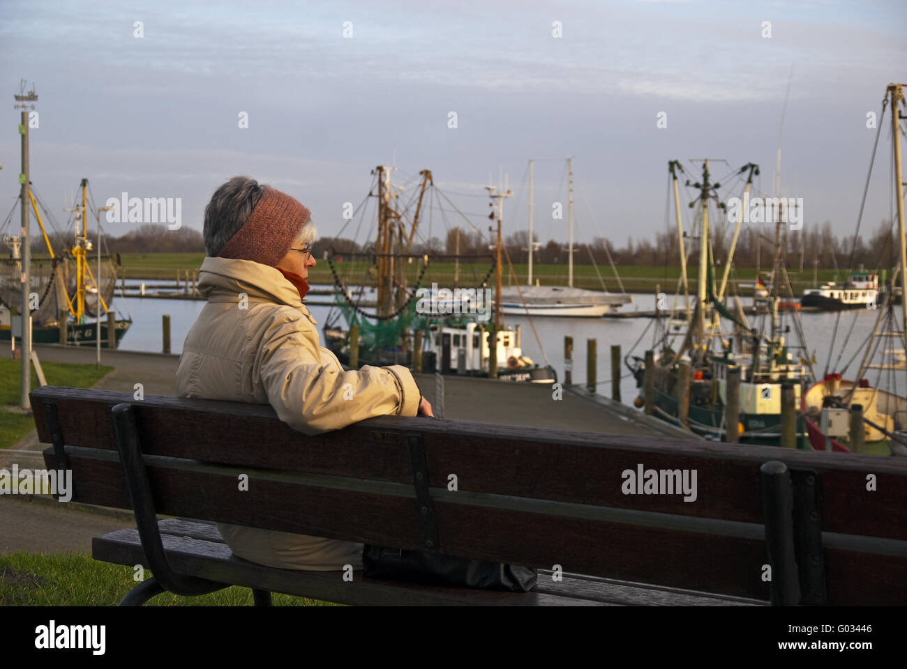 Woman sitting on a bench and watch ships in the ha Stock Photo