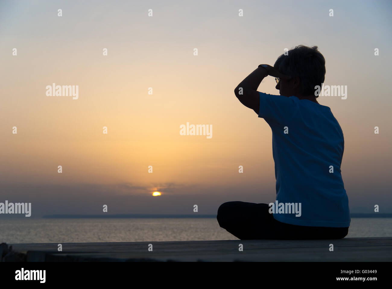 Woman sits on the coast of the Mediterranean and l Stock Photo