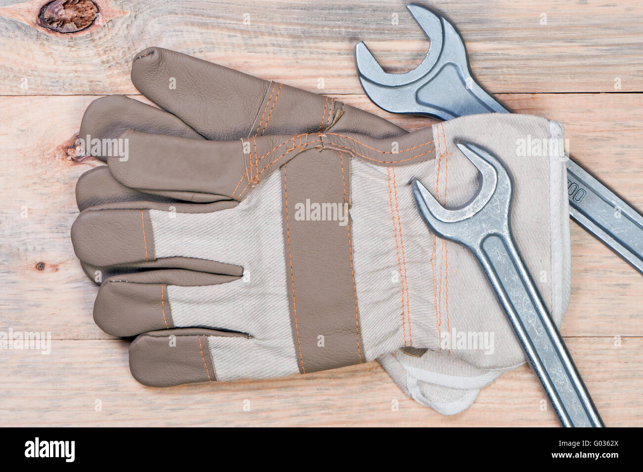 Work gloves and wrenches on wooden background. Stock Photo