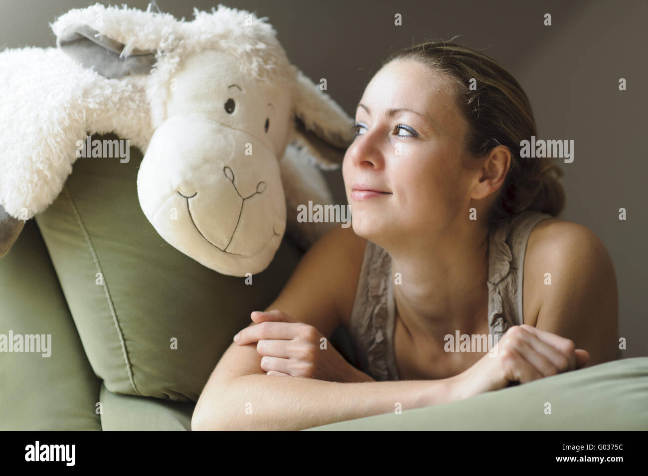 young woman lying on the couch with a stuffed anim Stock Photo