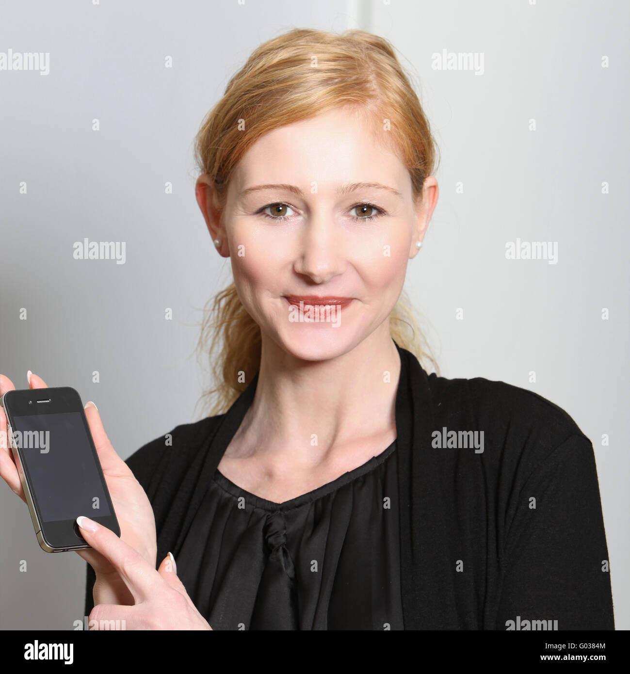 Young, smiling woman presented their smartphone Stock Photo