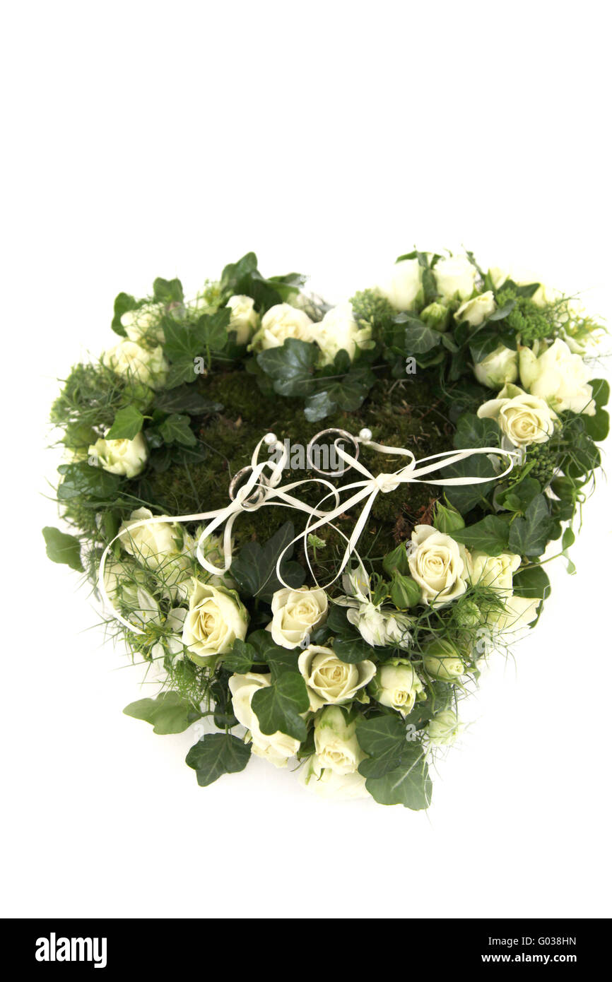 Wedding rings on a heart made of roses and ivy Stock Photo